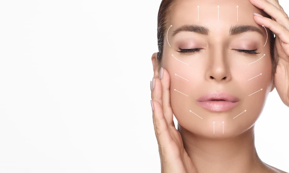 Woman touching her face with arrows showing lift and contouring effects, symbolizing collagen stimulation from Sculptra® treatment — What Is Sculptra® results.