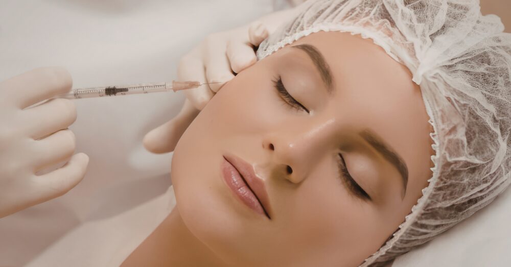 Close-up of a woman receiving a facial injectable treatment with a fine needle near the cheekbone area