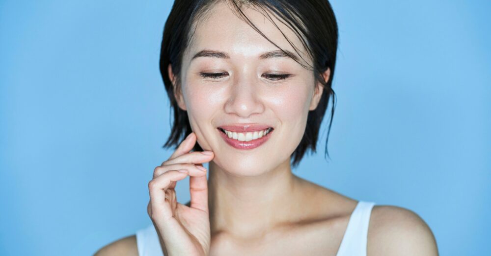 Woman smiling while looking down, against a blue background
