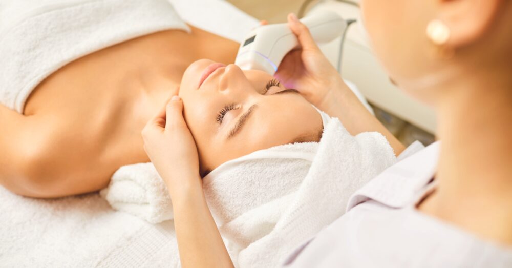 Woman lying down while receiving a facial treatment in a clinical setting